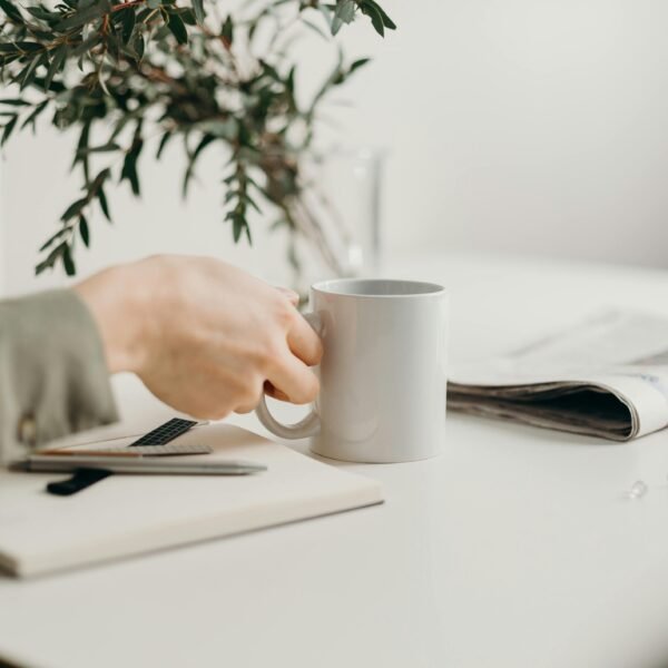 A minimalist workspace featuring a mug, notebook, and greenery, perfect for productivity.